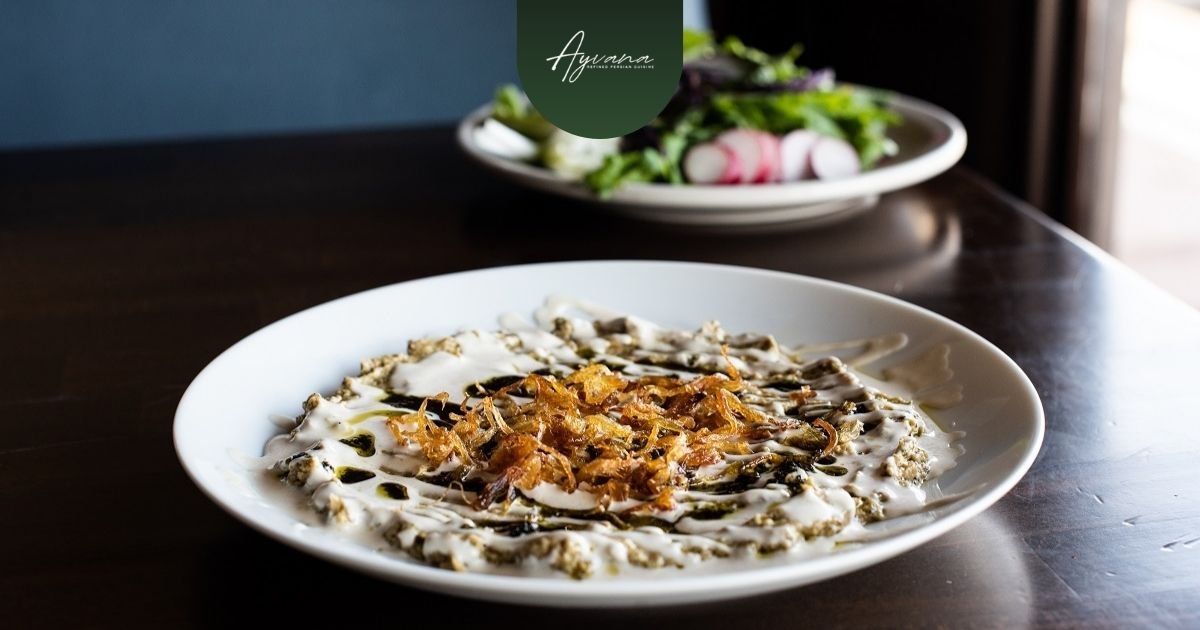 Plate of creamy Kashk-e Bademjan topped with crispy onions, featuring smoky savory Persian appetizer flavors and rich texture