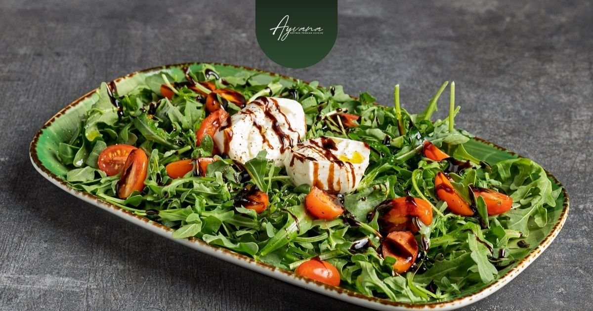 Fresh Sabzi Khordan: vibrant Persian herb platter with arugula, cherry tomatoes, burrata, and balsamic drizzle on green dish