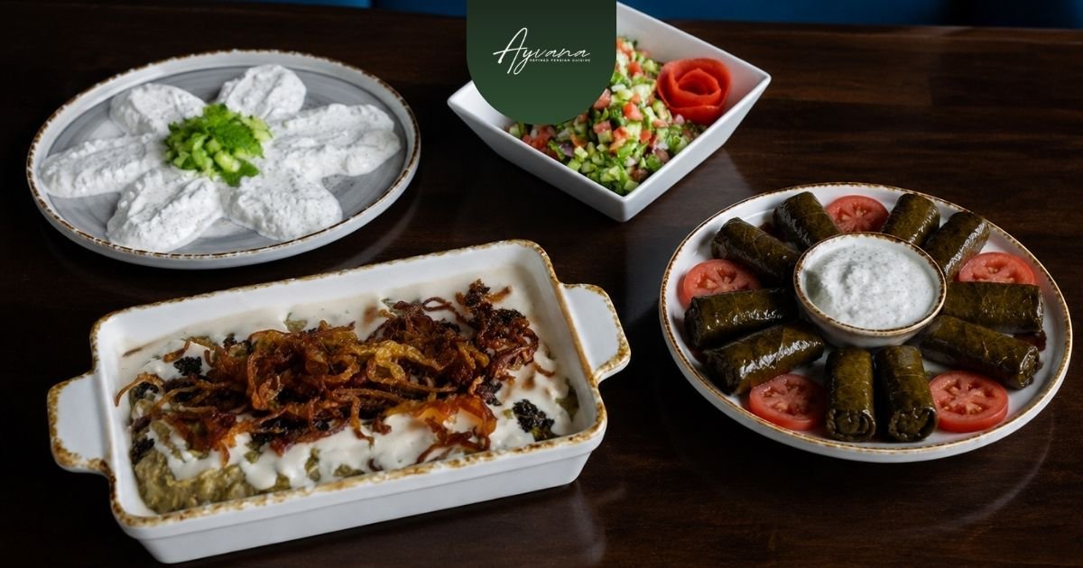 Persian appetizers for sharing including mast-o-khiar, shirazi salad, Kashk-e Bademjan, and dolmeh arranged on a communal table