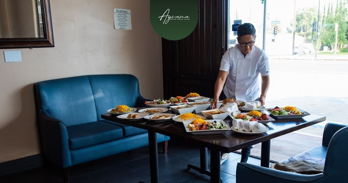 Chef preparing a table full of Persian dishes at Ayvana Persian Restaurant, ready for guests to enjoy