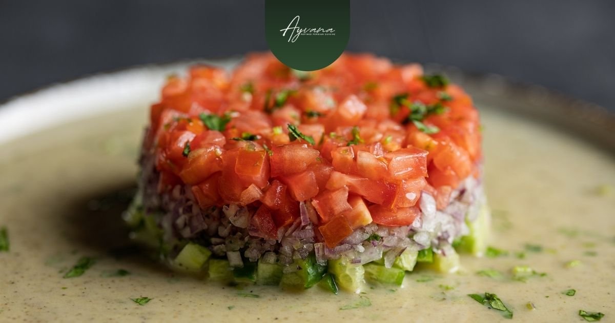 Close-up of a finely chopped Shirazi salad with diced tomatoes, cucumbers, and onions, elegantly molded and served on a creamy sauce at Ayvana.