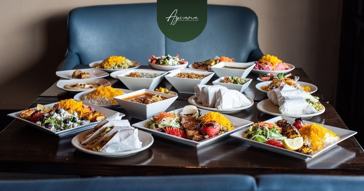 Table filled with Persian kebabs, stews, saffron rice, wraps, and appetizers inside Ayvana Persian Restaurant in Tarzana California